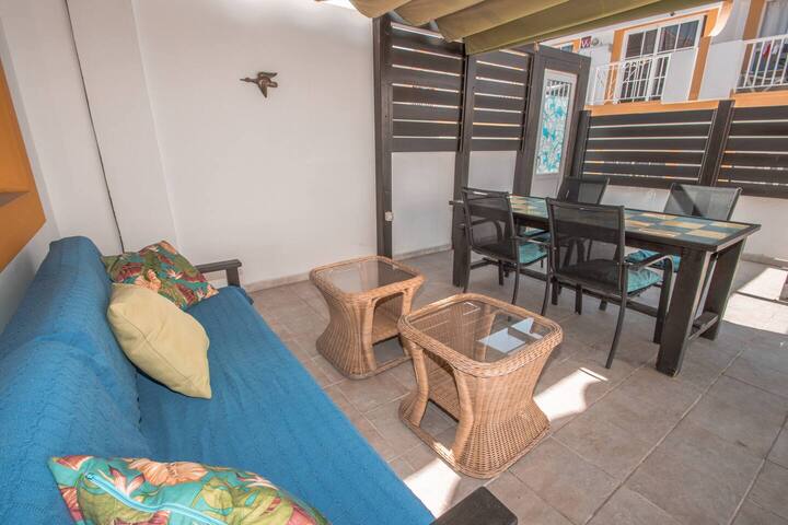 Rincón chill-out del patio con sofá y mesa: el sitio perfecto para relajarse a la sombra.