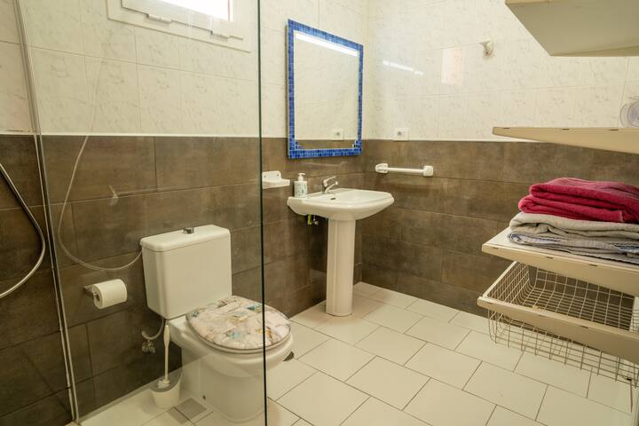 Baño con ducha de obra, lavabo de pie y espejo enmarcado en azul: amplio y muy cuidado.