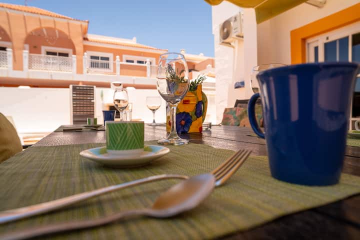 Detalle de la mesa exterior lista para comer, con las casas de la zona al fondo.