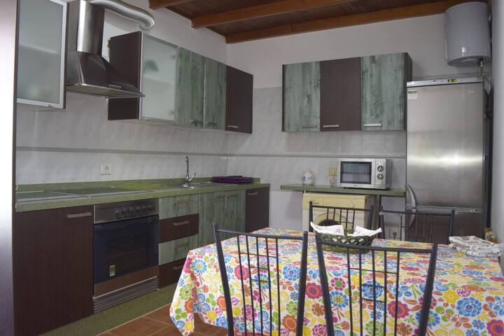 Cocina moderna con nevera grande, microondas y mesa: lista para preparar cualquier comida.