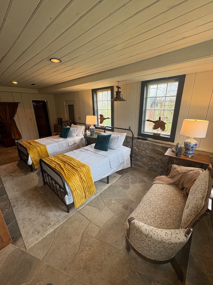 Garden level suite with 4 identical twin beds, 1 small couch, coffee table, and lounge chair. Private entrance to backyard with nearby access to bathroom with jacuzzi tub.