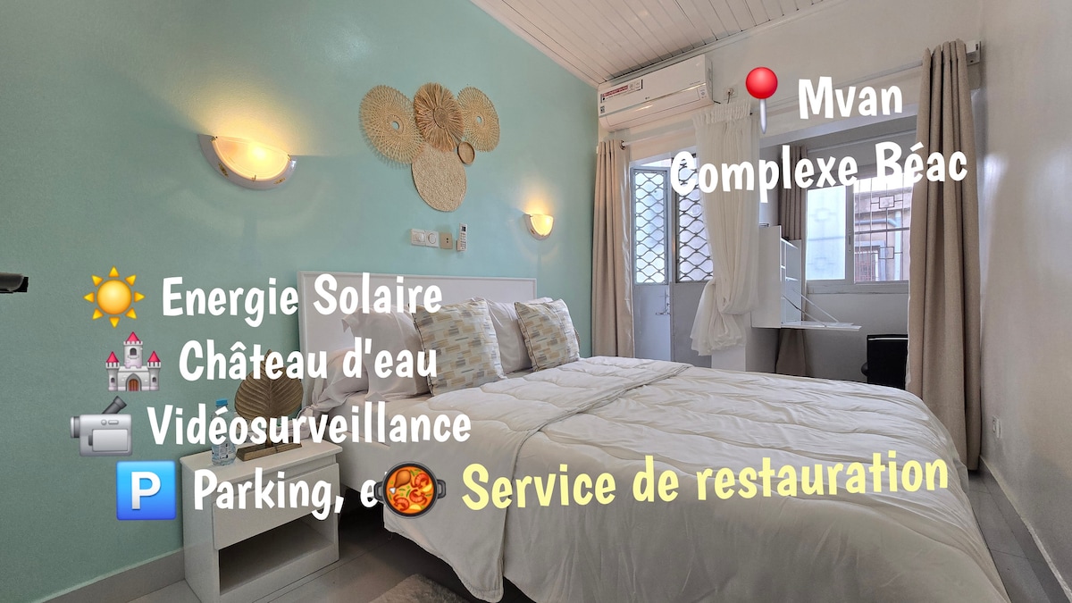 A well-lit bedroom features a spacious bed with light linens and decorative wall accents, including woven elements. Natural light filters through a window covered by sheer curtains, providing a calming ambiance. Information about available services is visible on the wall.