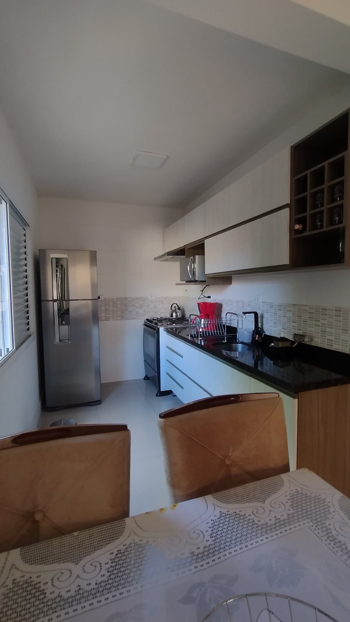 A modern kitchen is equipped with stainless steel appliances, including a refrigerator and a stove. A sleek countertop is paired with cabinetry, showcasing an organized space. An adjacent dining area is visible, featuring a table with four chairs, enhancing functionality within the open layout.