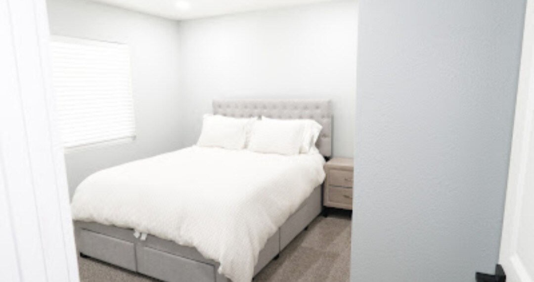 استمتع بالهدوء في غرفة نومنا الجميلة ذات الحجم الكبير، حيث تمتزج سجادة فاخرة وغطاء سرير أبيض هش وضوء الشمس الدافئ لخلق ملاذ مثالي للراحة والاسترخاء.