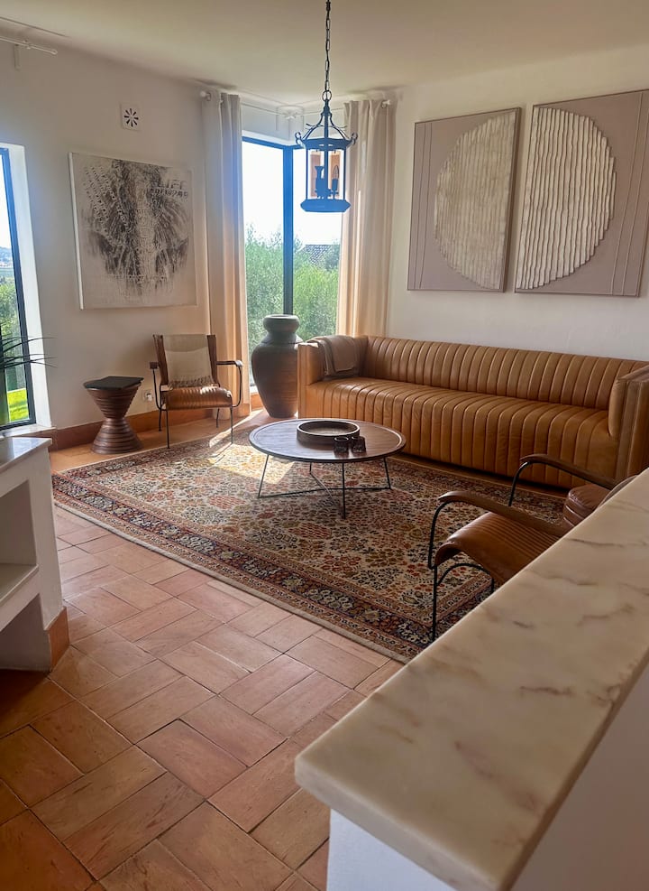 Всекидневна. Красив кожен диван е в центъра на стаята. Това е уютна и релаксираща атмосфера. Места за сядане за група. Зашеметяваща гледка към градината и лозето от пода до горните прозорци! Тук има и телевизор за стрийминг на закрито. 