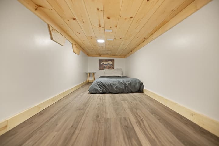 Cozy loft sleep nook with warm wood ceiling and minimalist comfort