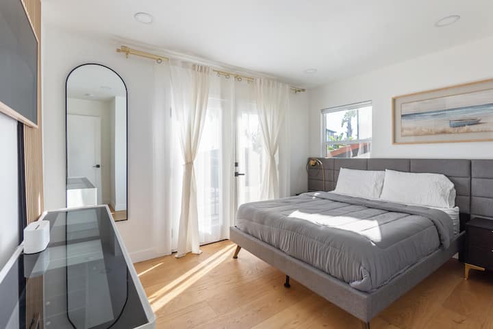 غرفة نوم ذات إضاءة جيدة مع سرير ملكي مريح وشرفة. 