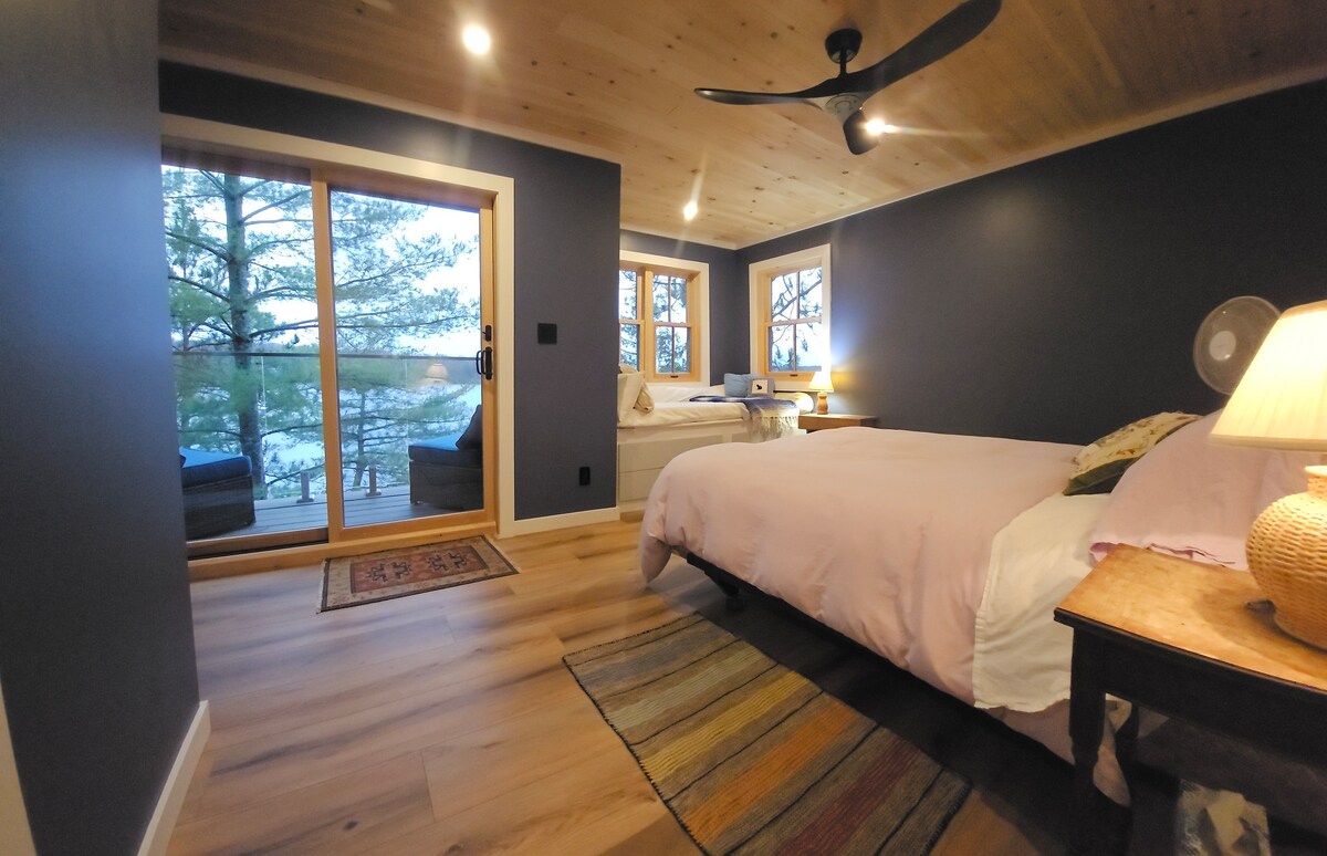 Un espacioso dormitorio principal en el segundo nivel, con su propio baño privado y terraza con vistas a las puestas de sol en el lago Belmont.