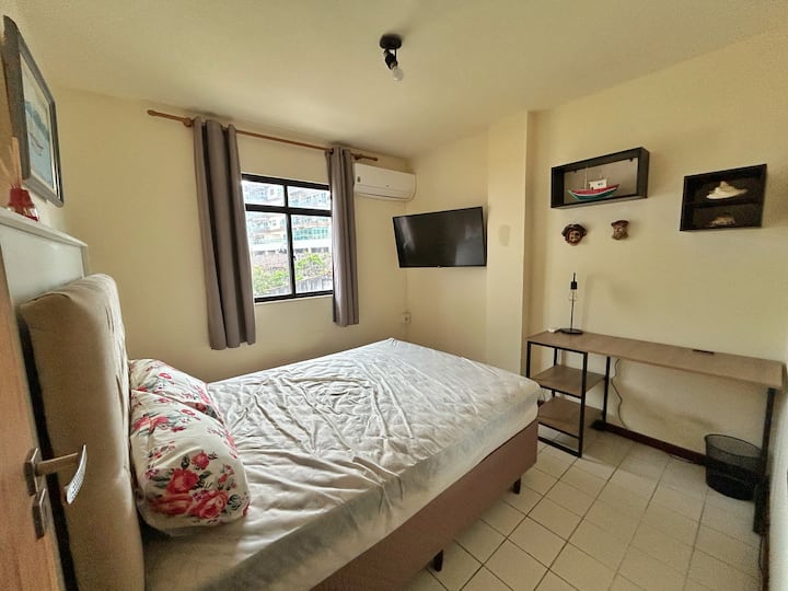 Manželská posteľ, televízor, klimatizácia, pracovný stôl v domácej kancelárii.