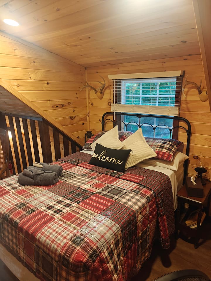 The full-size bed provides a cozy space for snuggling beneath the vaulted ceiling, with a warm ambiance created by the electric fireplace.