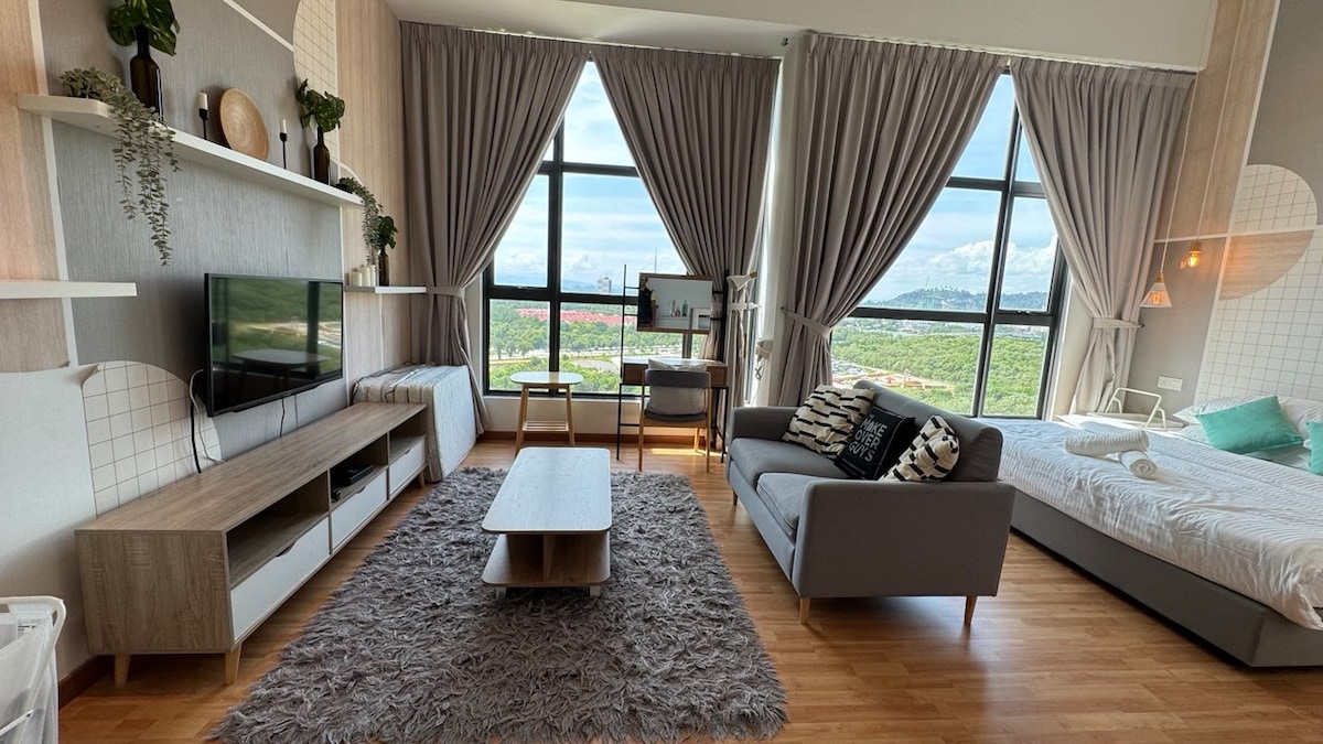 A modern living space features large windows allowing natural light to illuminate the area. A comfortable sofa faces a TV mounted on a decorated wall. A coffee table is centered on a soft rug, while a spacious bed is positioned in the background, complemented by neutral tones.