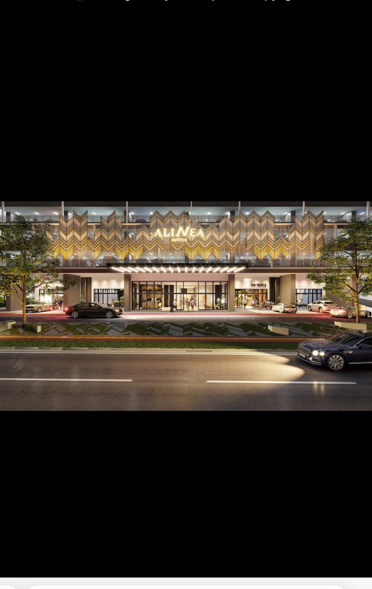 The serviced apartment building showcases a modern architectural design with distinctive fluted wall panels. Bright lighting illuminates the entrance, and a well-maintained exterior landscape features trees and potted plants. Vehicles can be seen parked nearby along the road, creating an accessible, inviting atmosphere.