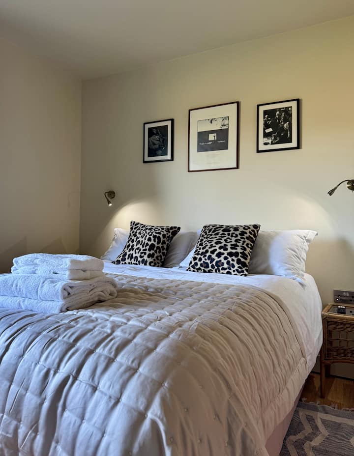 سرير بحجم كبير وطاولات جانبية مع أضواء قراءة بزاوية. أفضل أغطية الأسرّة من فئة 5 نجوم من مغسلة شورتريدج.  تلفزيون ذكي مثبت على الحائط.