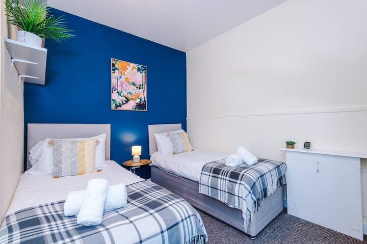Encantador dormitorio con dos camas individuales que se convierten en una doble, elegantes detalles azules y toques acogedores para una estancia relajante.