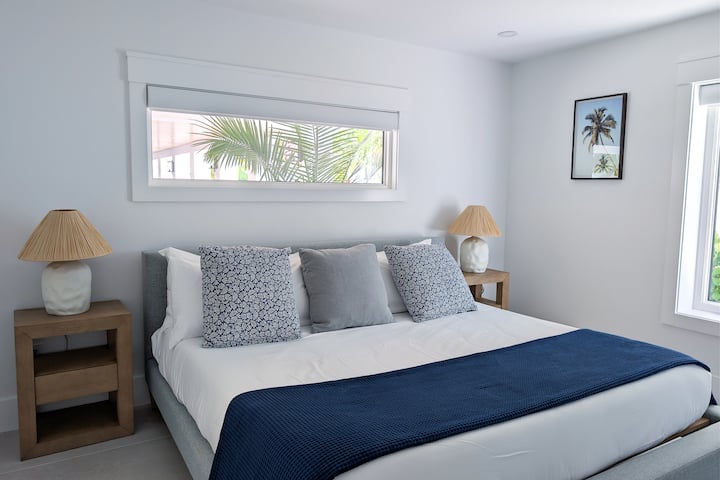 Ground-floor bedroom with a sliding door that opens onto the courtyard/pool, featuring an outdoor kitchen. Shared full bathroom directly across the hallway.