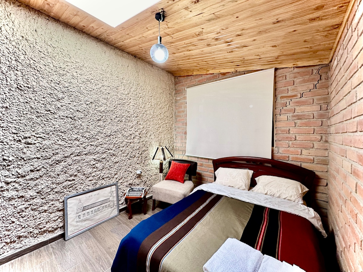 חדר שינה שני עם מיטת קווין סייז, ארון, שמיכות נוספות וכיסא קריאה.