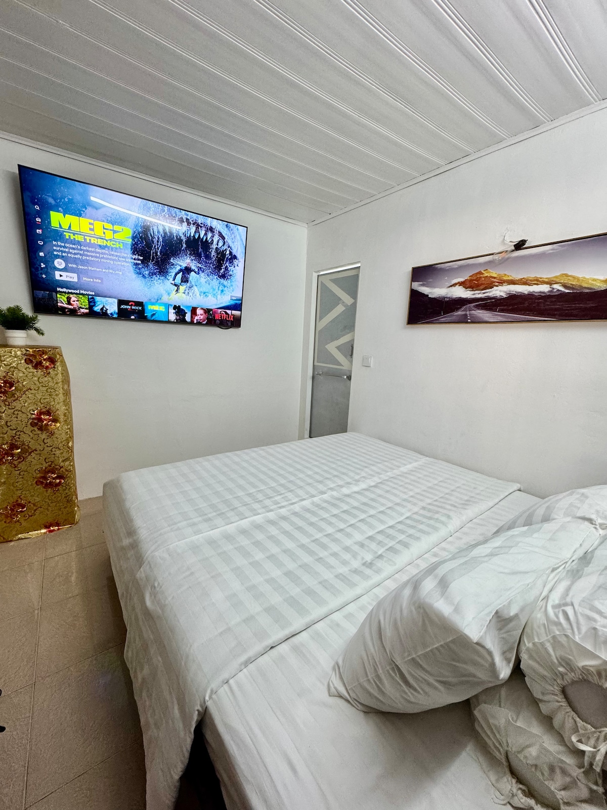 A blurred image is seen, suggesting a cozy sleeping area. Soft bedding may be present, accompanied by light-colored walls and a textured ceiling above. The image captures an intimate and serene environment intended for relaxation.