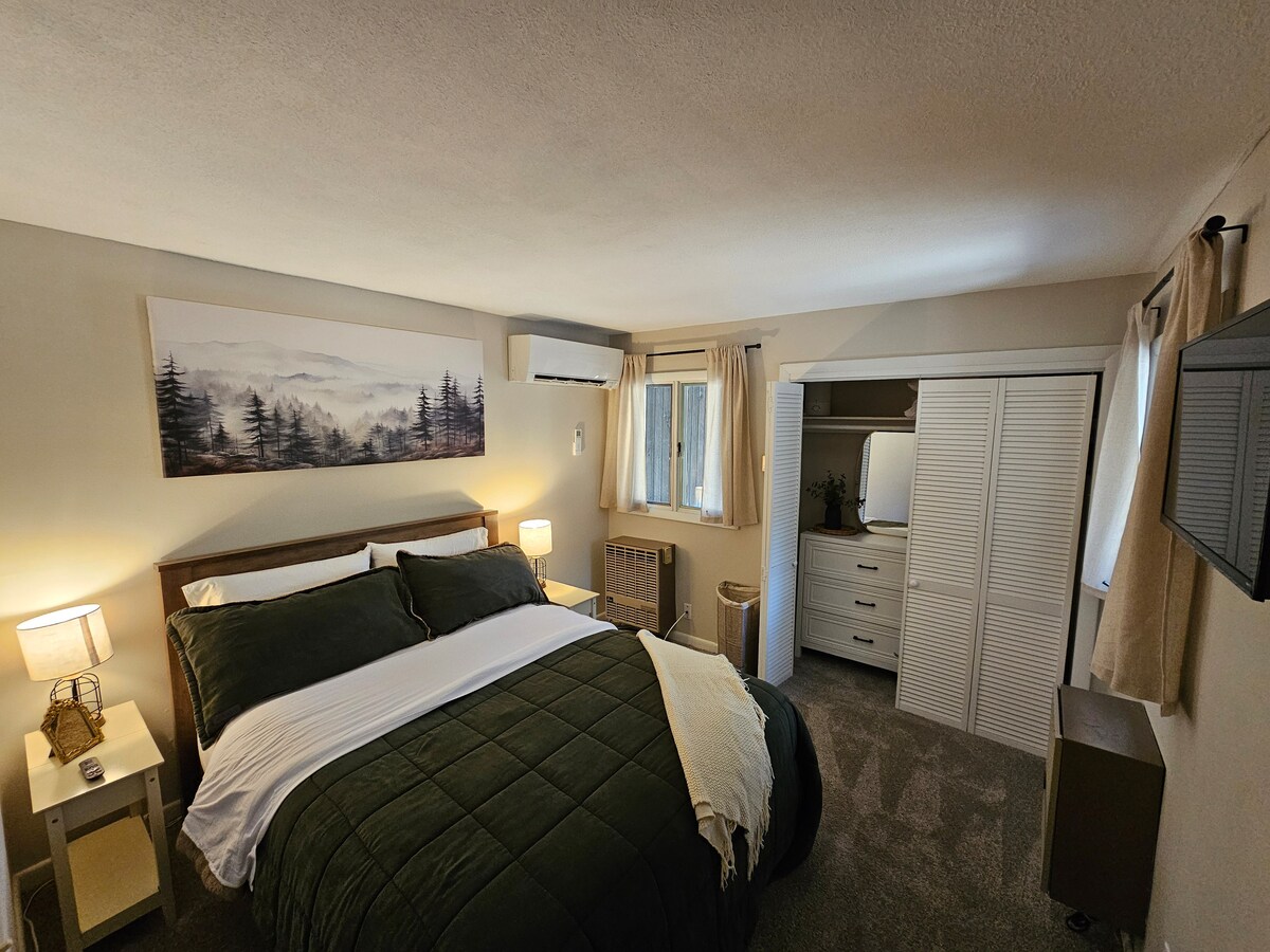 Dormitorio luminoso y acogedor en el primer piso con aire acondicionado, TV montada en la pared, armario y vestidor.