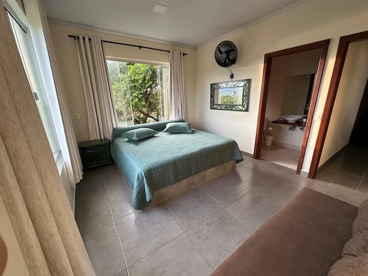 Quarto aconchegante com vista incrível para a natureza e o lago, equipado com uma cama confortável, sofá-cama para um hóspede extra e suíte privativa. Perfeito para relaxar e apreciar a paisagem.