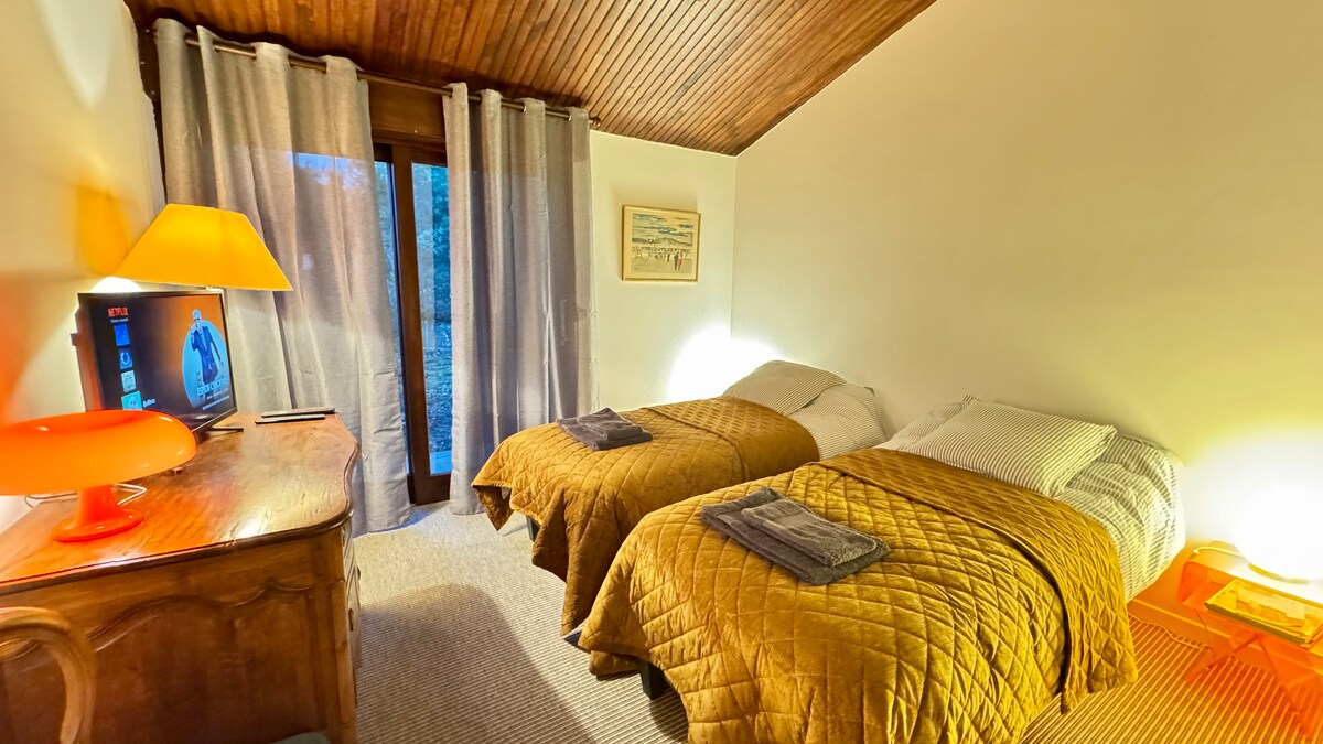 חדר שינה  עם 2 מיטות נפרדות וטלוויזיה.