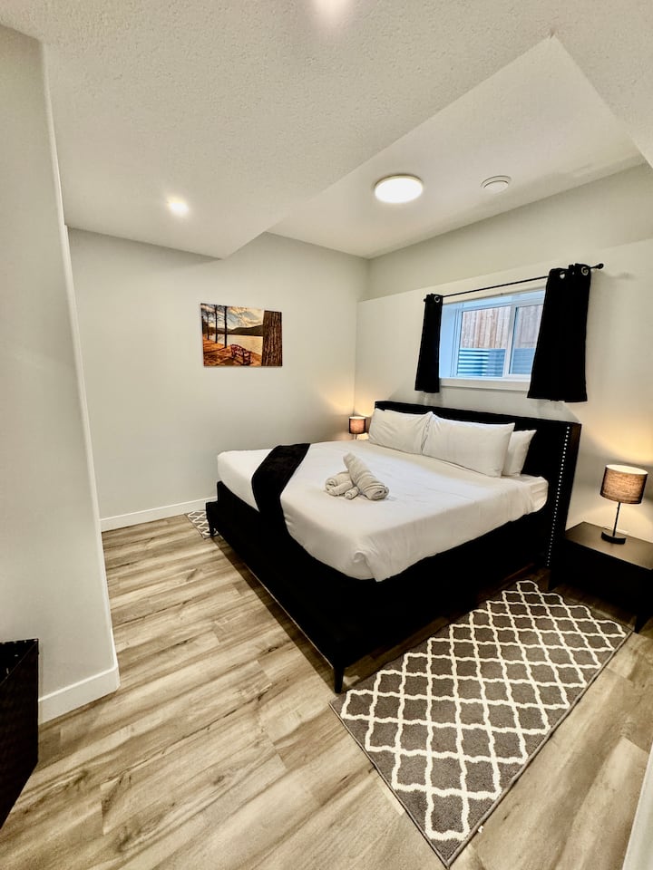 Chambre au sous-sol avec plafonds de 10 pieds, grandes fenêtres pour beaucoup d'éclairage naturel, éclairage bicolore à intensité variable, lit king size, chauffe peignoir (avec draps, oreillers et couvertures supplémentaires)