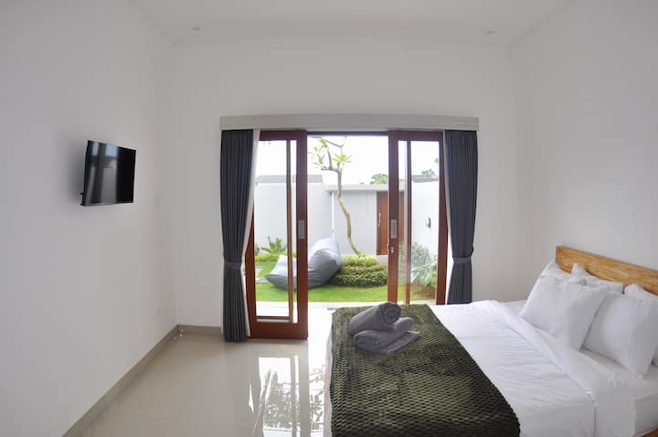 Una lujosa cama tamaño king en una habitación bellamente diseñada equipada con aire acondicionado, TV de pantalla plana y baño privado. La habitación se abre directamente a la piscina al aire libre y ofrece una conexión perfecta a una experiencia serena oasis.