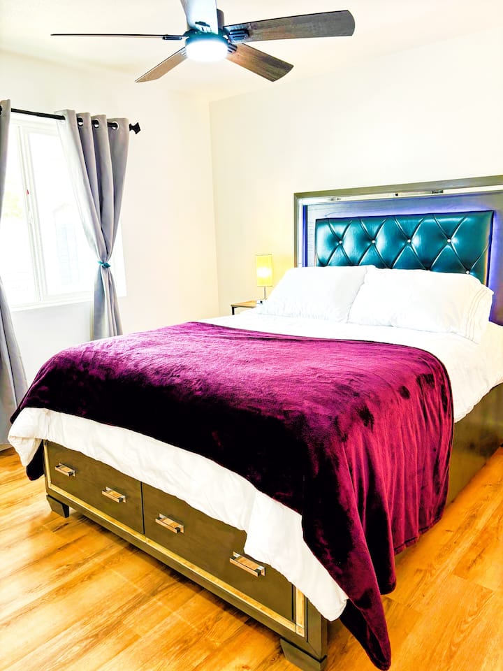 ห้องนอนใหญ่ควีนไซส์โครงเตียงขนาดใหญ่พร้อมที่เก็บตู้เสื้อผ้าที่มีอุปกรณ์ครบครันพอร์ตชาร์จไฟและไฟสวยงาม 