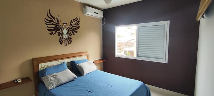 Quarto aconchegante e bem equipado, com TV Smart, ar-condicionado, espaço para malas e roupas. No corredor, frigobar exclusivo para hóspedes. A decoração é de bom gosto e a vista para o morro nos fundos da casa traz um charme adicional.