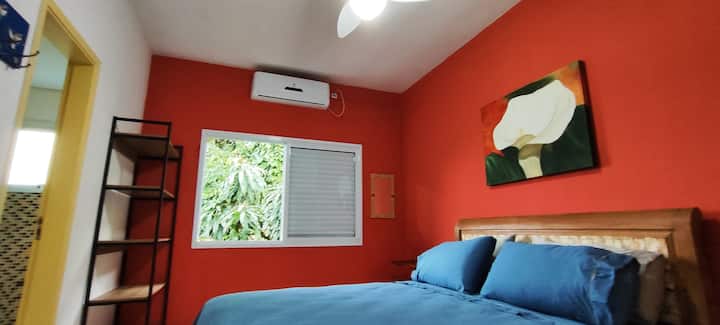 Quarto aconchegante e bem equipado, com TV Smart, ar-condicionado, espaço para malas e roupas. No corredor, frigobar exclusivo para hóspedes. A decoração é de bom gosto e a vista para o morro nos fundos da casa traz um charme adicional.