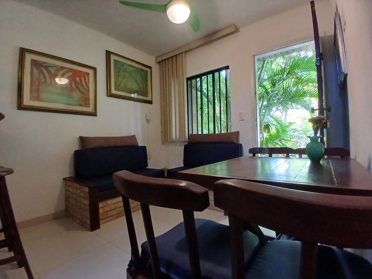 חדר מרוהט עם ספה, שולחן וכיסאות המשקיף על הגינה עם מטבח