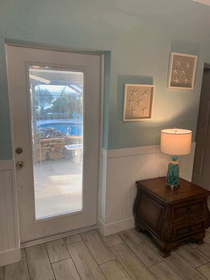 ประตูหน้าหลักพร้อมมินิบลายด์ในประตู มองเห็นสระว่ายน้ำ น้ำตก และทะเลสาบได้โดยตรงจากห้องนอนและลานระเบียงนี้