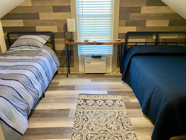 Two twin XL beds and two full beds. The upstairs bedroom is one large room with partial partition walls, a total of four beds. Upstairs ceiling height is 6 ft 3 in. Luggage racks provided at the foot of each bed.