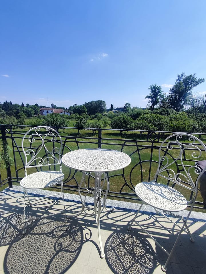 Lys privat balkon med elegante udendørs siddepladser, perfekt til morgenkaffe eller en afslappende aperitif. Nyd fredfyldt udsigt til grønne områder og solskin i rolige boligomgivelser.