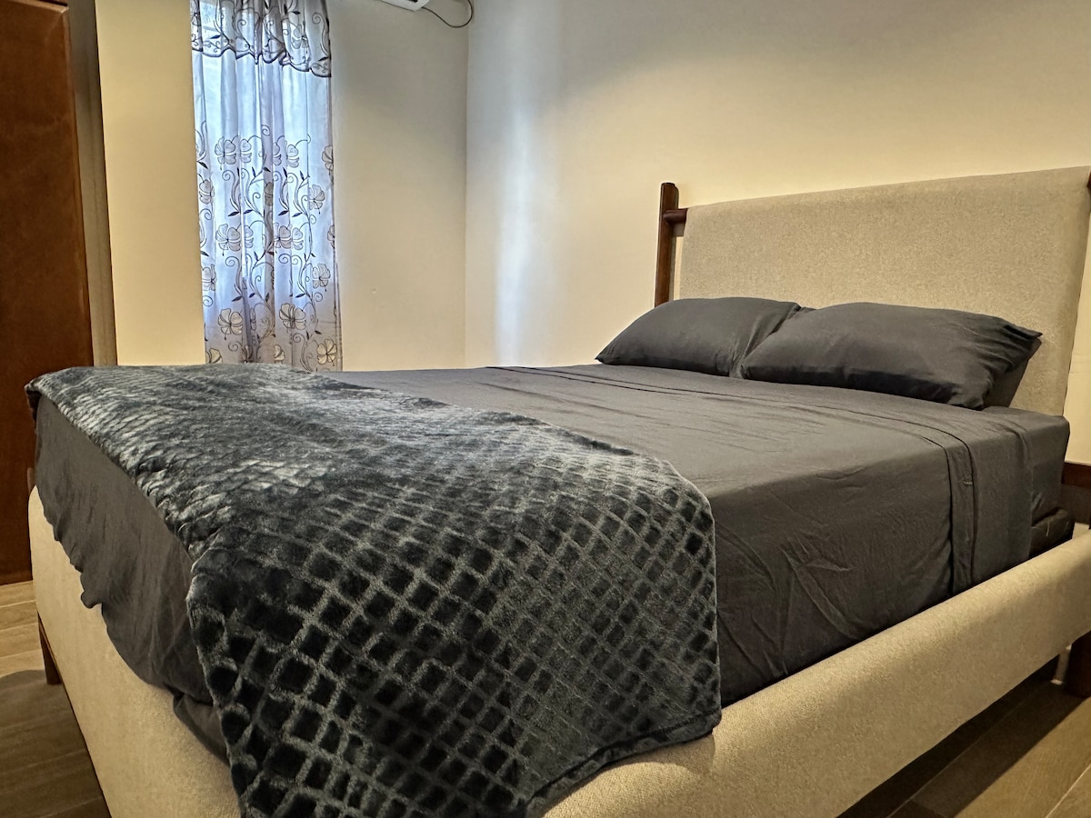 חדר שינה שקט בגודל קווין סייז עם גוונים ניטרליים רכים, וילונות האפלה ומצעים מפנקים.  אידיאלי למשפחות או לאנשי מקצוע שמחפשים מנוחה ונוחות אחרי הקרנבל או יום עמוס.