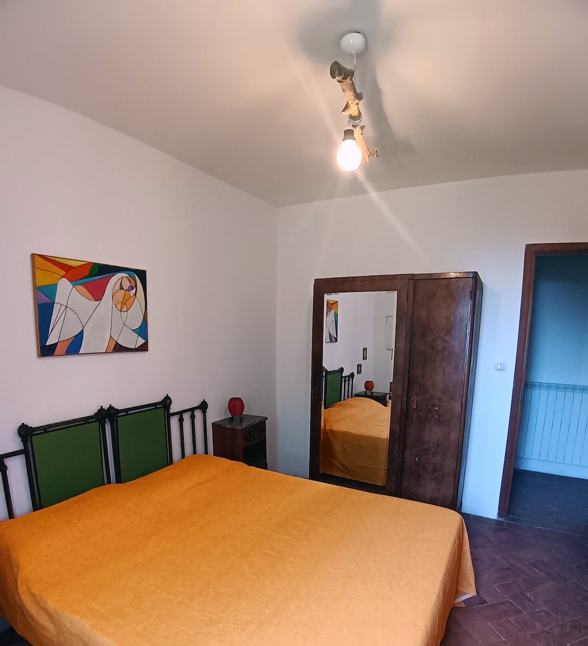 חדר שינה עם מיטה זוגית, ארון בגדים ונוף מהחלון. 