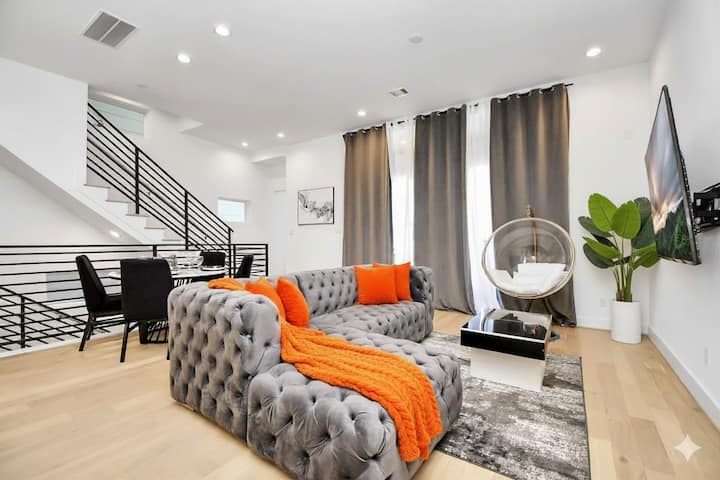 Влезте в нашата зашеметяваща всекидневна, където естествена светлина се влива през просторни стъклени врати, осветяващи плюшени удобства: разтегателен диван, 75 - инчов телевизор, елегантна трапезария, емблематичен яйчен стол и разтегателна масичка за съхранение,