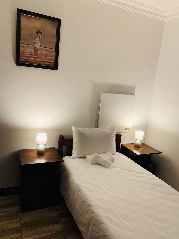 תמונה זו מציגה את מיטת הסleigh היחידה, המצוידת במצעים ומגבות איכותיים, המשקפים את הסטנדרטים של חדרי השינה האחרים. אנחנו מספקים גם שידות לילה ומנורות. התנור ויצירות האמנות הנוספות נראים גם בתצוגה הזו.

