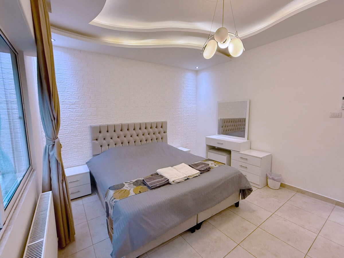 Un segundo dormitorio acogedor y elegante con una cómoda cama tamaño king, iluminación suave y una cálida decoración; diseñado para ofrecer a los huéspedes un refugio tranquilo y acogedor.