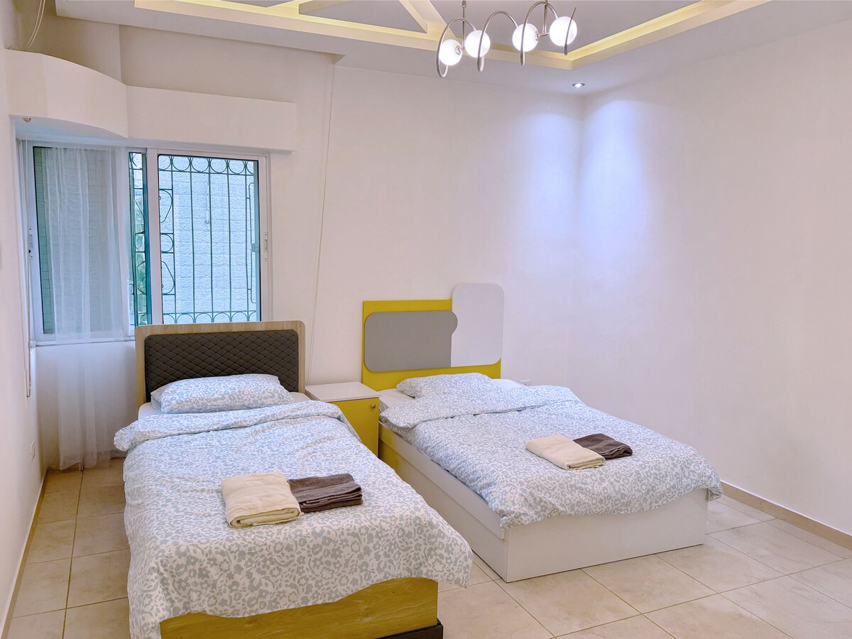 Una habitación doble luminosa y cómoda con dos acogedoras camas individuales, iluminación suave y una cálida decoración familiar; ideal para niños, amigos o huéspedes adicionales.