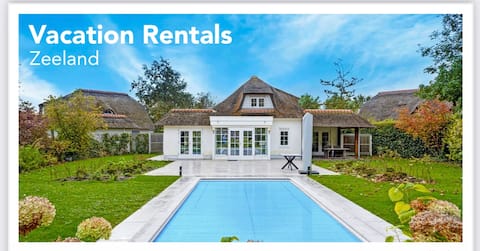 Luxury beach house in park-like garden with swimming pool.