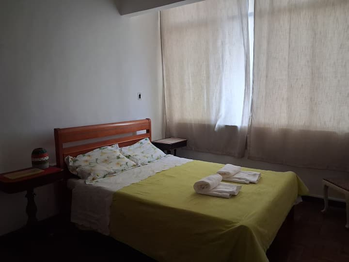 Habitación muy espaciosa con una cama doble y mesitas de noche. 