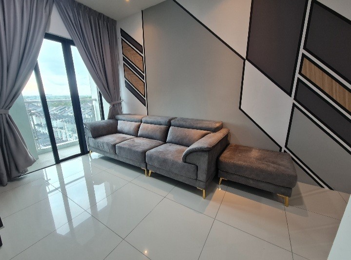 A modern living area features a sectional gray sofa with a chaise lounge, positioned against a striking accent wall. Floor-to-ceiling windows allow natural light to fill the space, while gray drapes frame the view of the surrounding landscape.