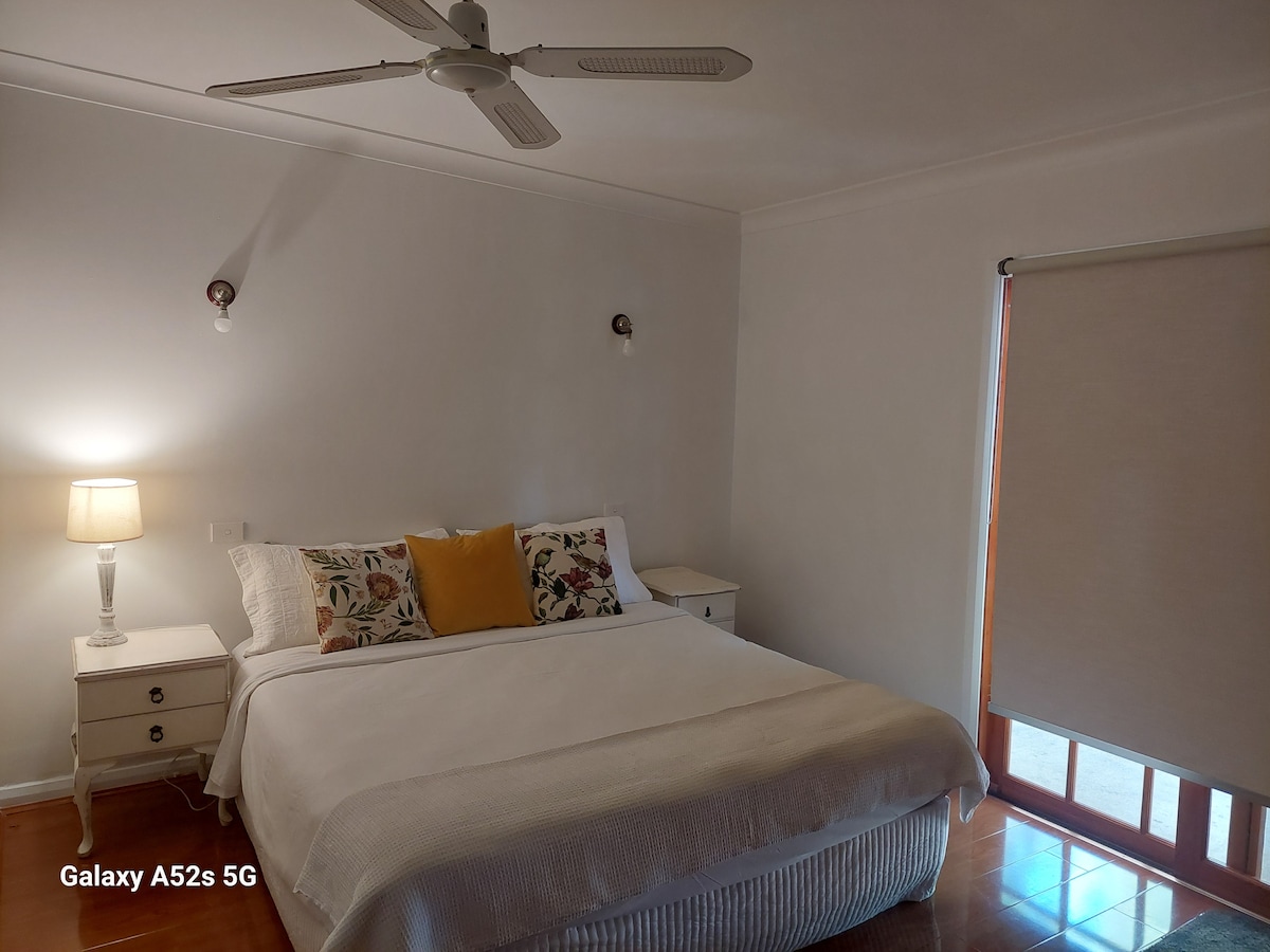 1 lit king size 2 tables d'appoint et lampes, ventilateur de plafond et accès au jardin arrière