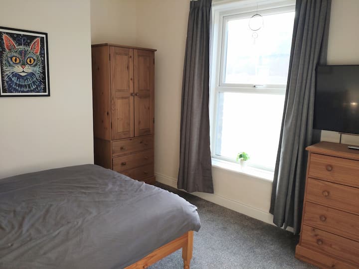 בחדר השינה הזה יש את כל מה שהייתם מצפים לו, יחד עם טלוויזיה חכמה ותחנת עבודה תלויות על הקיר.