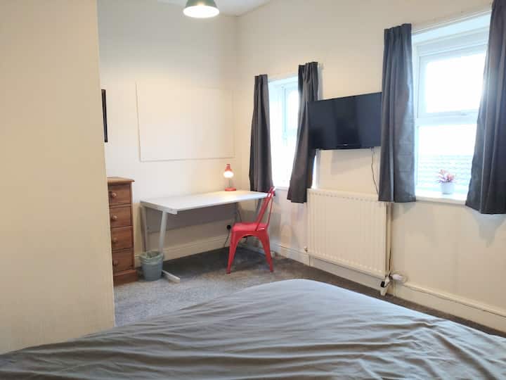 בחדר השינה הזה יש את כל מה שהייתם מצפים לו, יחד עם טלוויזיה חכמה ותחנת עבודה תלויות על הקיר.