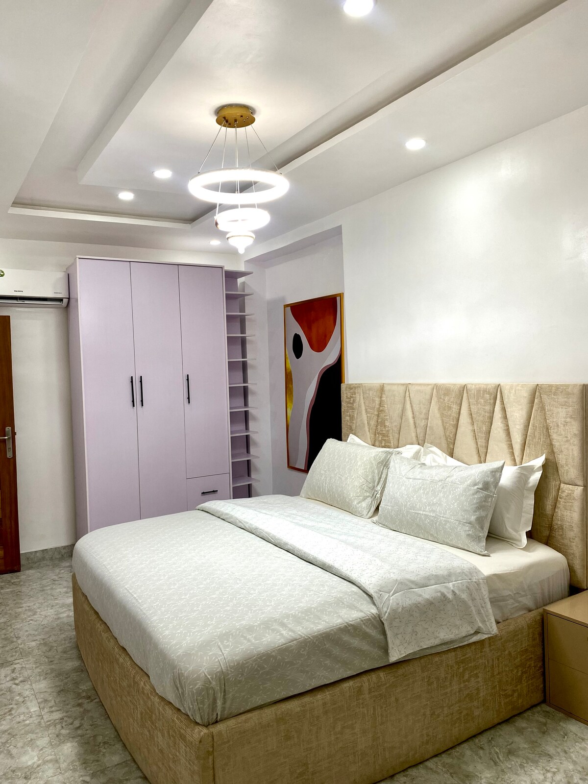 Elegante dormitorio con cama tamaño queen, iluminación cálida y amplio armario.