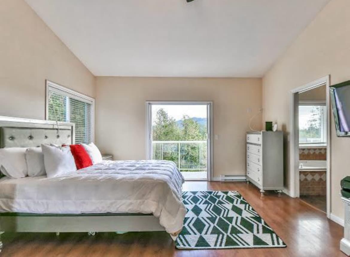 ห้องนอนกว้างขวางพร้อมเตียงคิงไซส์ตู้เสื้อผ้าพรมและประตูที่นำไปสู่ห้องน้ำในตัว สไตล์โมเดิร์นและเรียบง่ายด้วยการผสมผสานสีสันที่เป็นกลาง