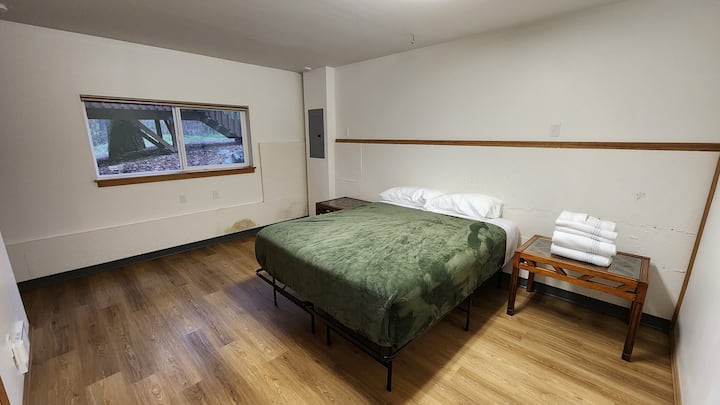 Manželská posteľ v bonusovej izbe v suteréne s denným svetlom.  Táto izba je na konci chodby, ale nemá dvere, ktoré by ju zatvorili zo zvyšku domu. Kúpeľňa v suteréne je medzi touto izbou a priestorom obývacej izby v suteréne.