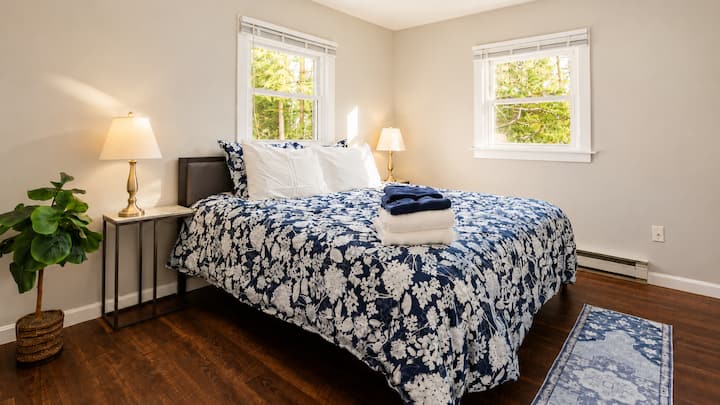 Rest on the queen bed after a day out, grab a fresh towel set close by, or open the windows for a view of the trees. The potted plant in the corner adds a bit of green to the room.
