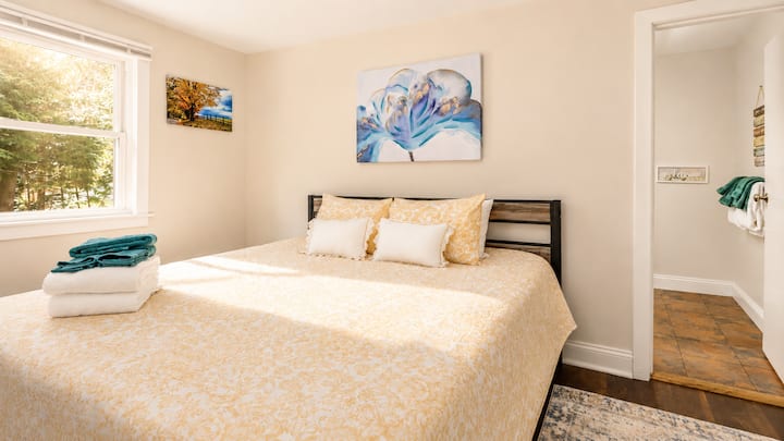 Rest on the king bed after a day out, grab a fresh towel from the stack close by, or head into the private bathroom just steps away. Open the window for a view of the trees while morning light fills the room.